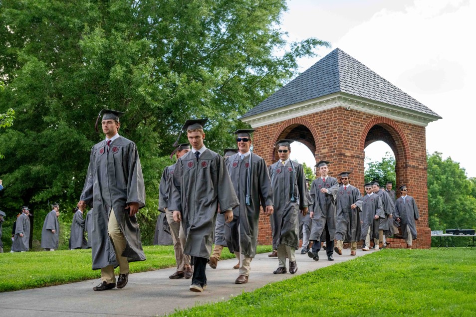 graduates processing in front of the bell tower