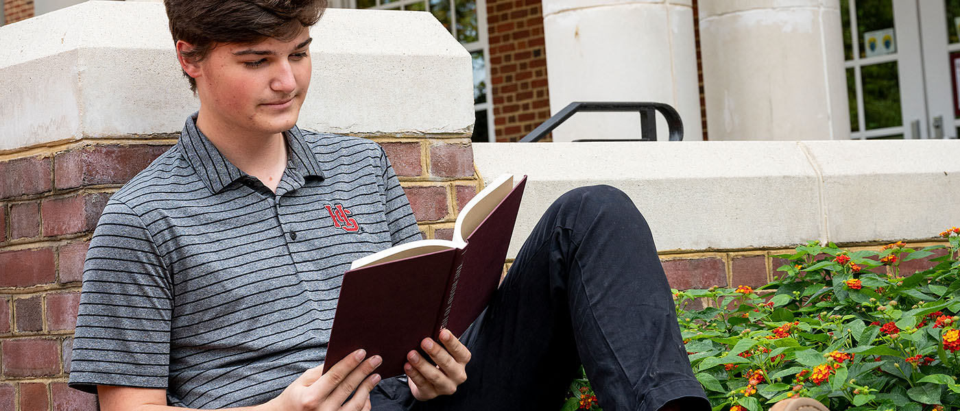 Student sitting outside reading a book