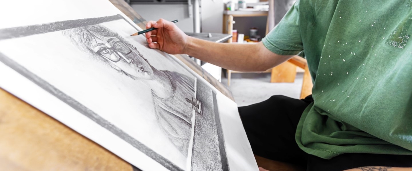 Student drawing a face on paper with pencil