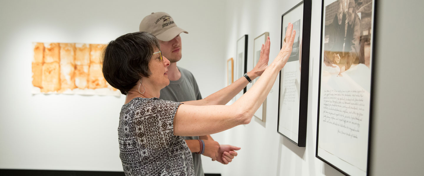 Professor Fox and student looking at artwork in the gallery