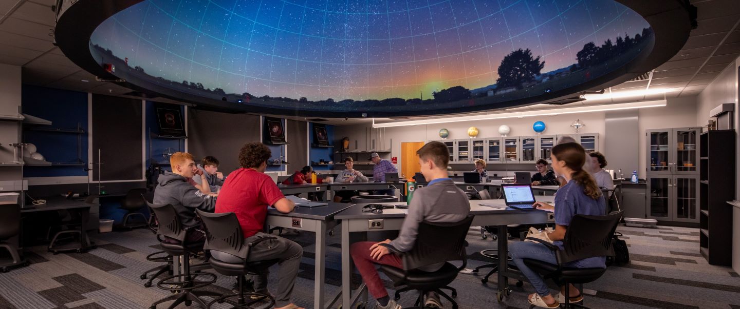 Students sitting beneath an astronomy planetarium