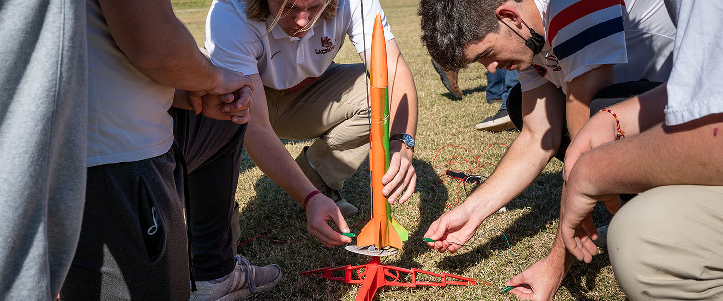 Students outdoors preparing a rocket for launch