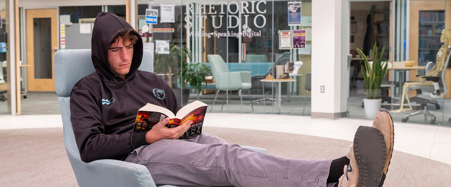 Student lounging and reading a book in the RhetoricStudio