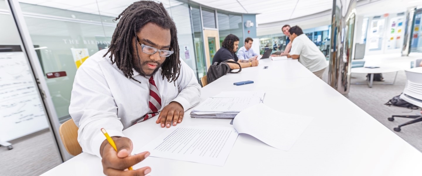 Hampden-Sydney student poring over a paper at a desk