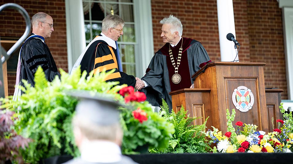President Stimpert shaking hands with George Will, speaker, at the podium