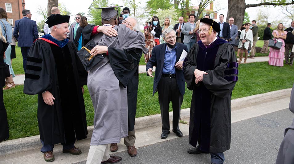 Students and professors hugging at commencement