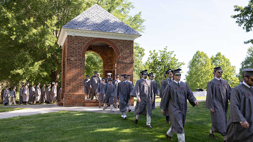 Commencement 2024 graduates in regalia marching throughthe Bell Tower