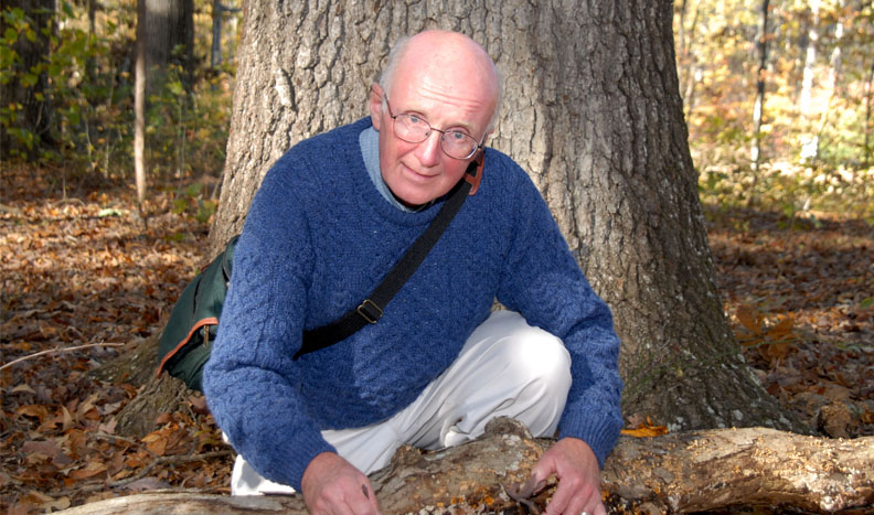 Dr. William Shear crouching by a tree