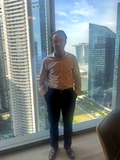 Zane Moody '18 in front of the Singapore skyline from his office