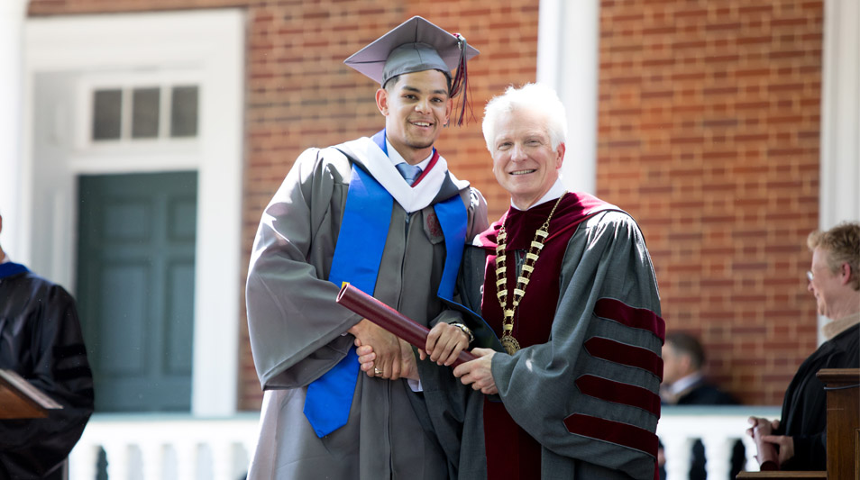 A graduate receives his diploma from President Stimpert.