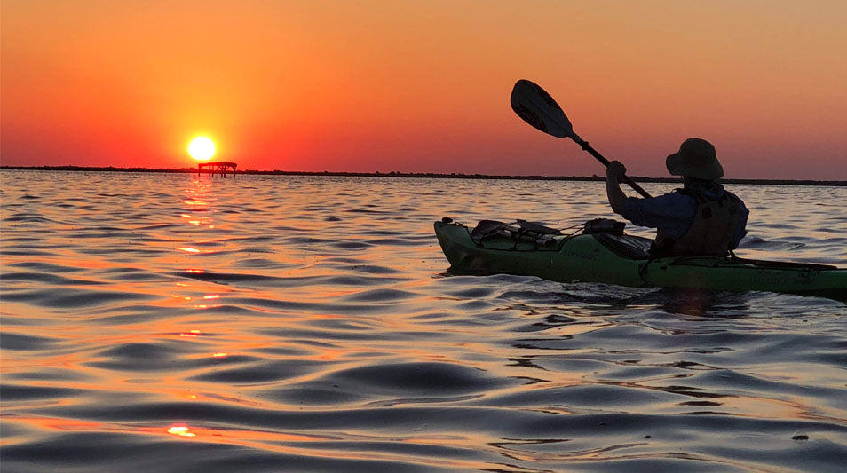Thomas Watson kayaks on the Pamlico River at sunset.