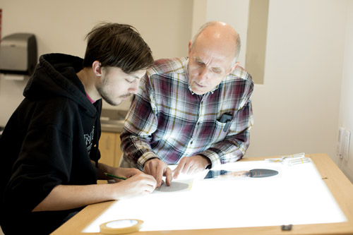 David Lewis helps a student with a drawing