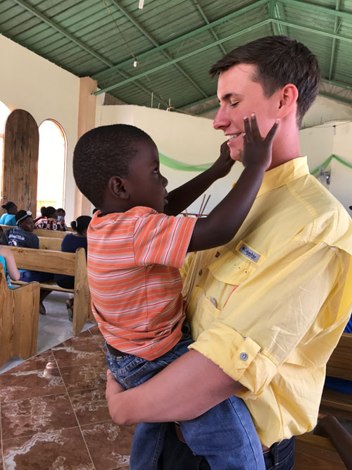 Tanner Beck holds a child on a service trip