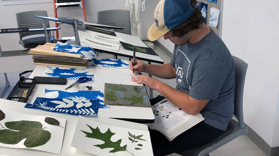 a student working on mounting leaves in the art studio