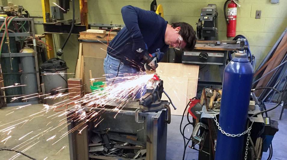 a student working in a machine shop with sparks flying
