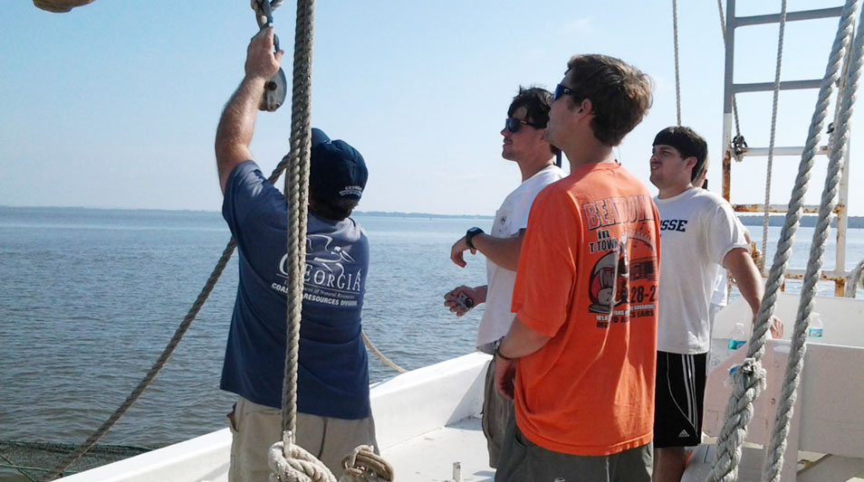 students on a shrimp boat working on the rigging