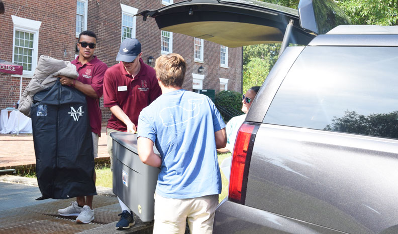 Students unpack a car to move into their new dorm