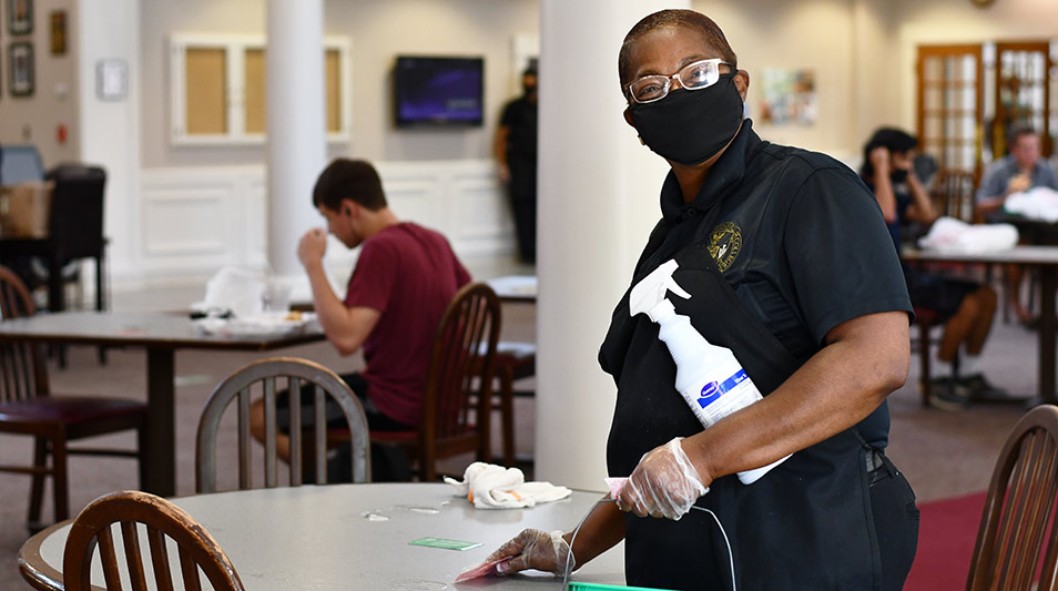 a woman cleaning a table in the dining hall