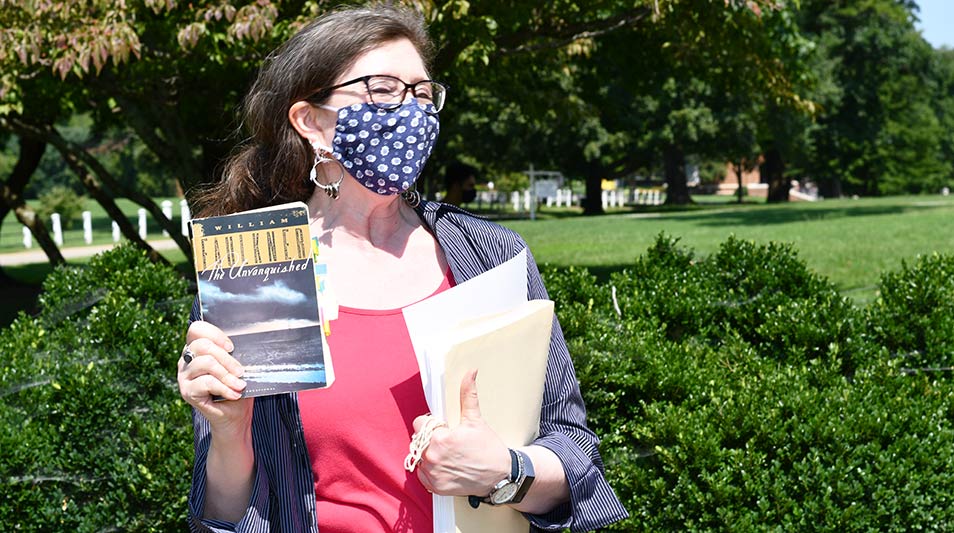 Dr. Hardy holding a book and wearing a mask