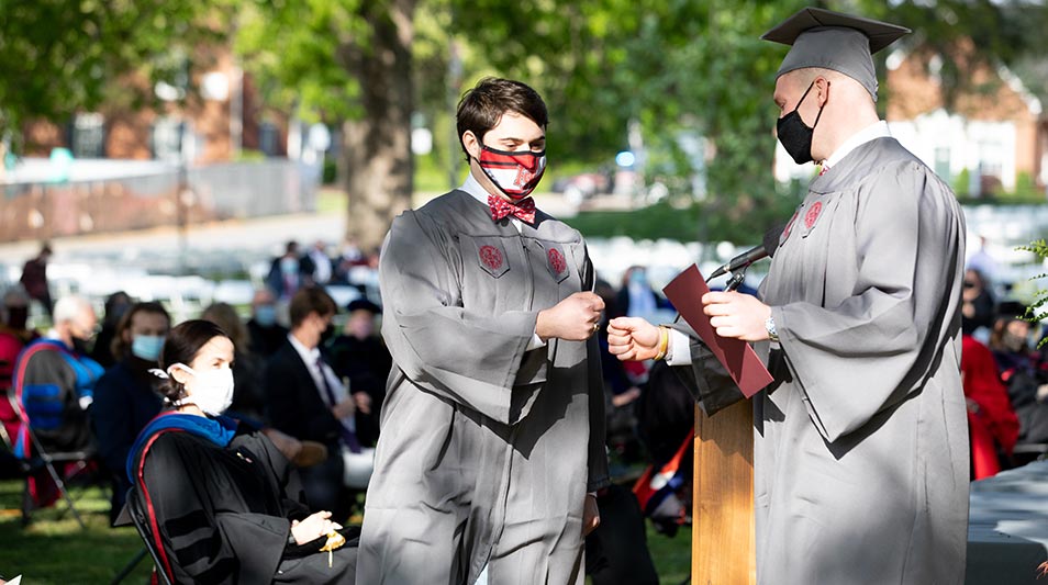 Hampden-Sydney students in regalia fist bumping in celebration