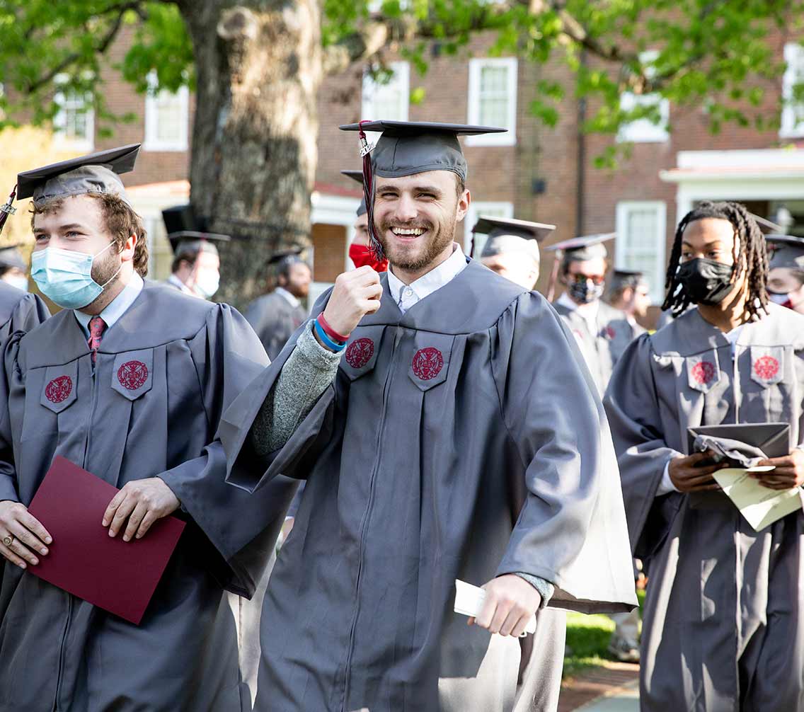 Hampden-Sydney student in academic regalia smiling at outdoor convocation