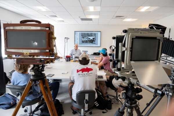 Brian Grogan discussing photography with student in class, with antique cameras in the foreground