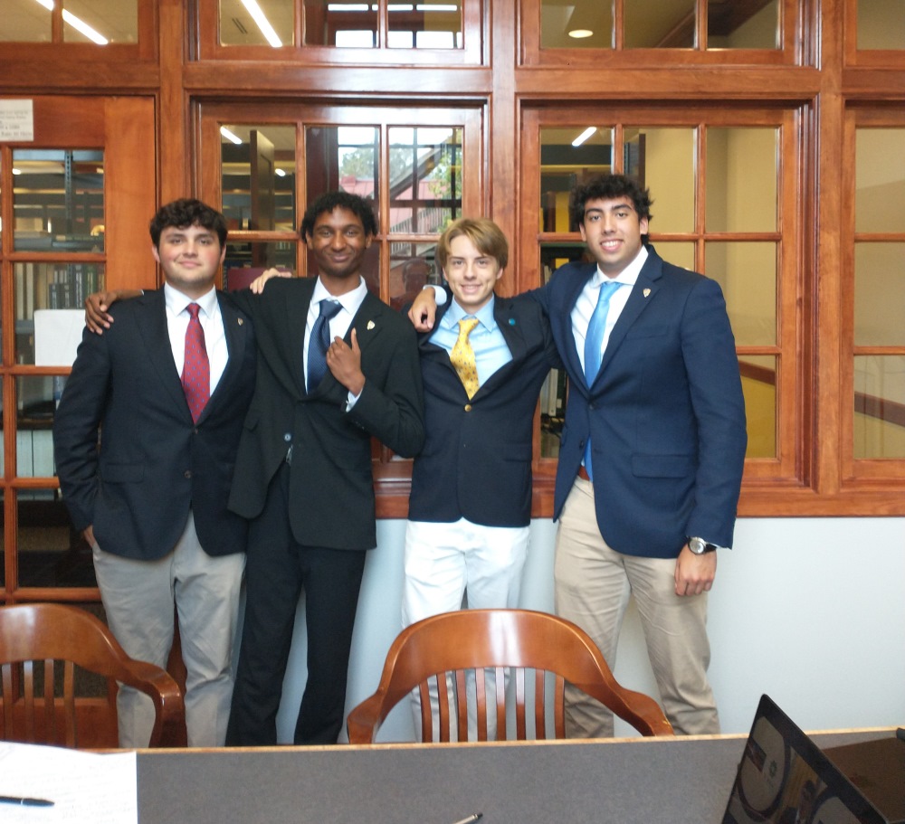 Four students posing in coat and tie