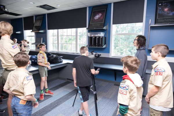 scouts in uniform looking through a telescope in a lab