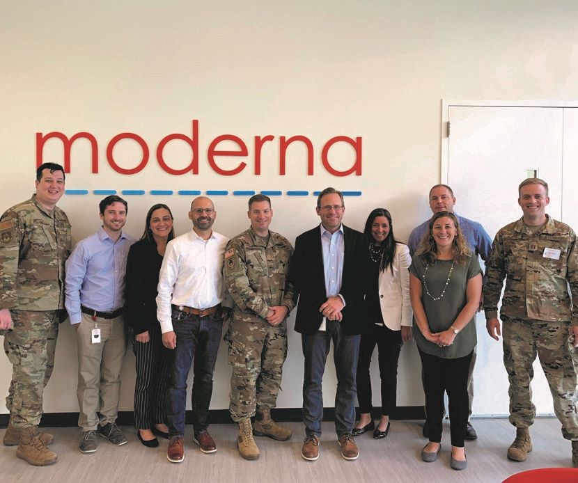 Scott Nickerson '95 standing with colleagues in front of a Moderna sign