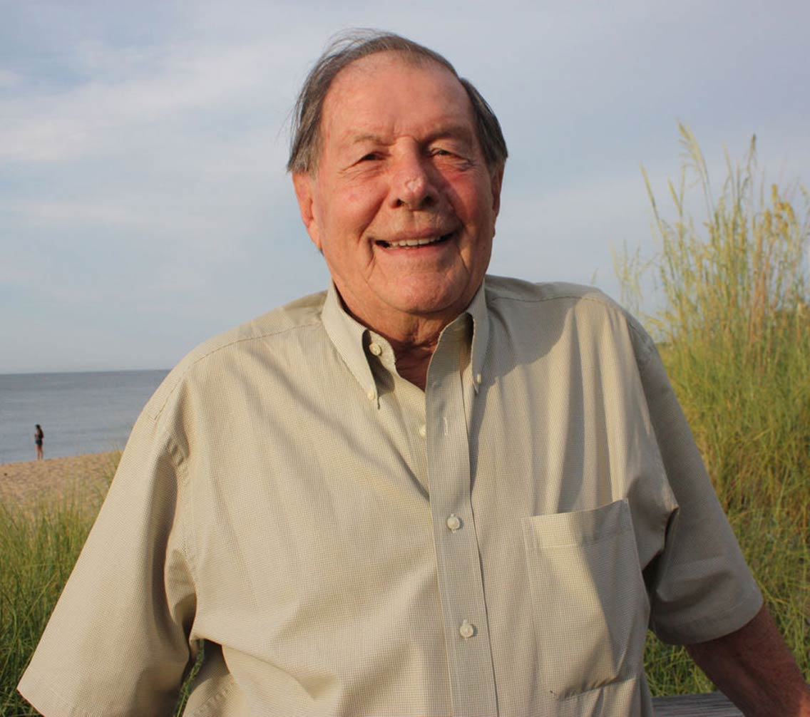 Clancy Holland '52 in front of a beachscape