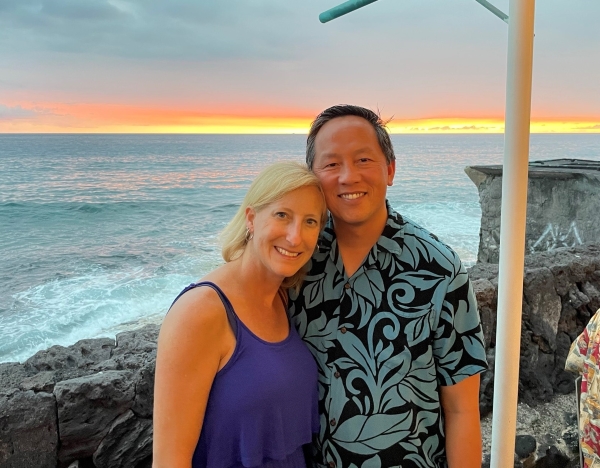 Steve Ho and his wife standing in front of a sunset