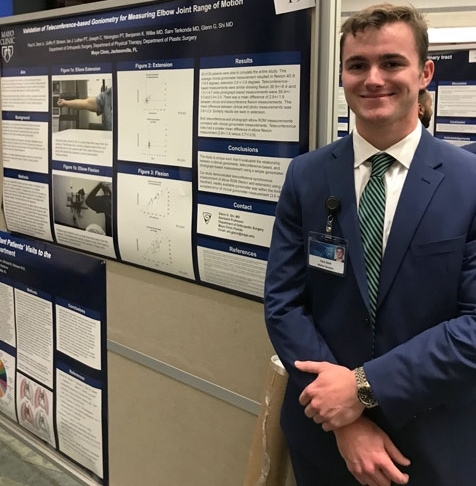 Alex Dent standing beside his research poster