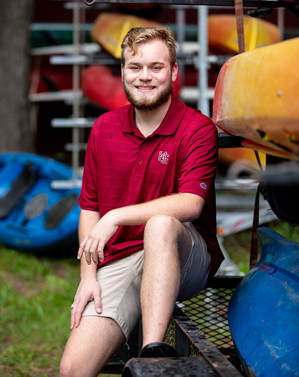 Harrison Whaley '21 sitting on a kayak rack