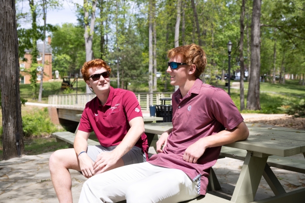The Lasso brothers casually sitting outdoors at a picnic table talking