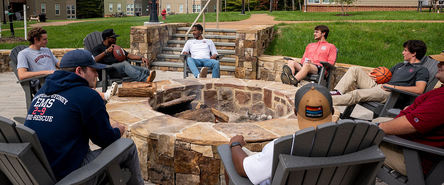 Hampden-Sydney College friends sitting around an outdoor firepit talking