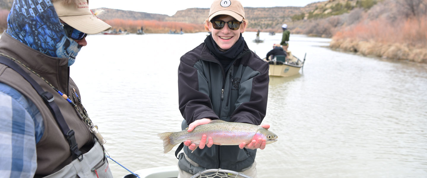 Hampden-Sydney student in a boat showing a fish on his fly fishing trip