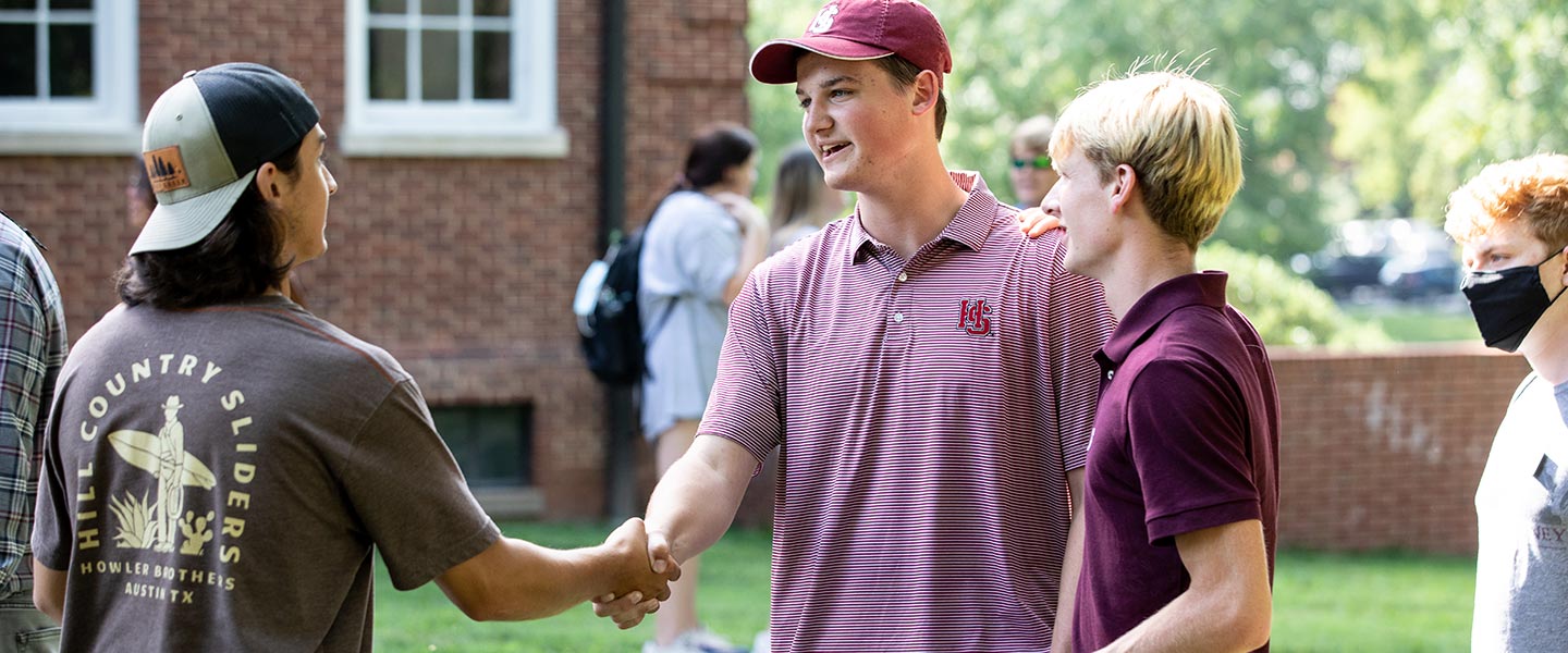 Young men shaking hands at an outdoor event