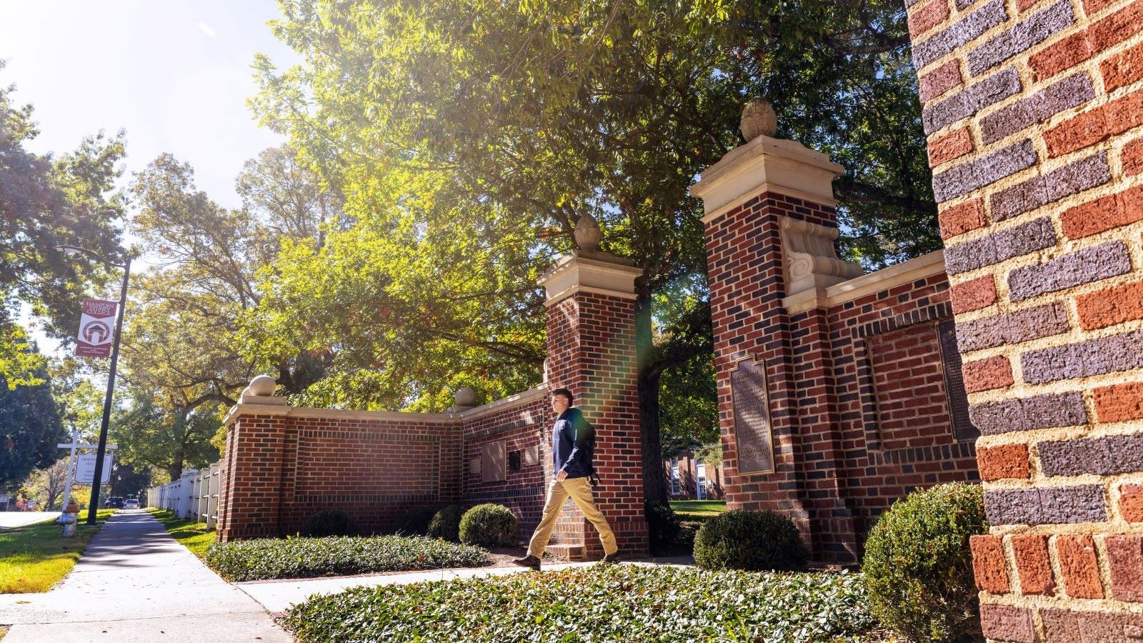 Student walking through Memorial Gates at Hampden-Sydney College
