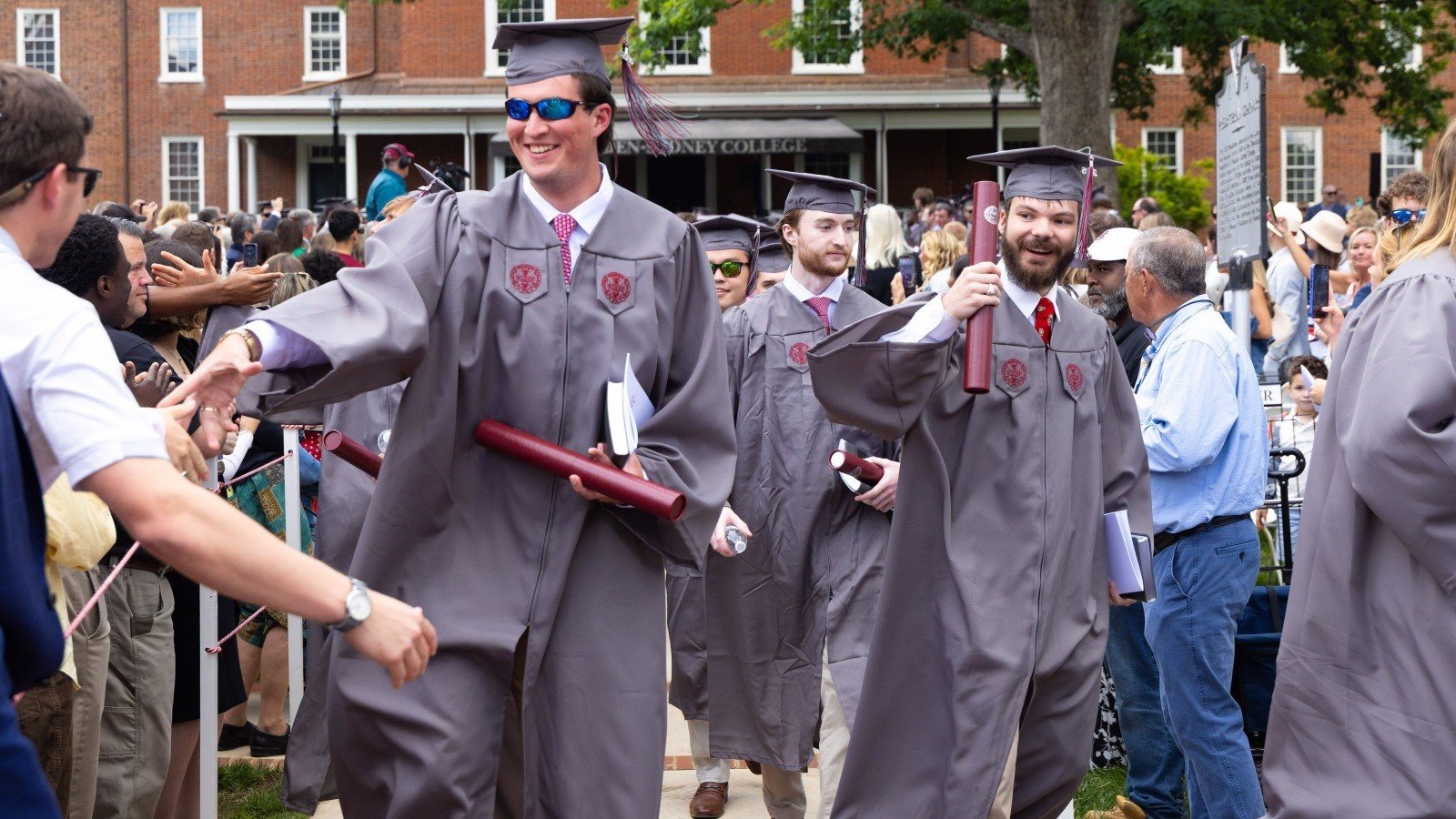 Graduating students in regalia leaving the commencement ceremony with diplomas in-hand at Hampden-Sydney College