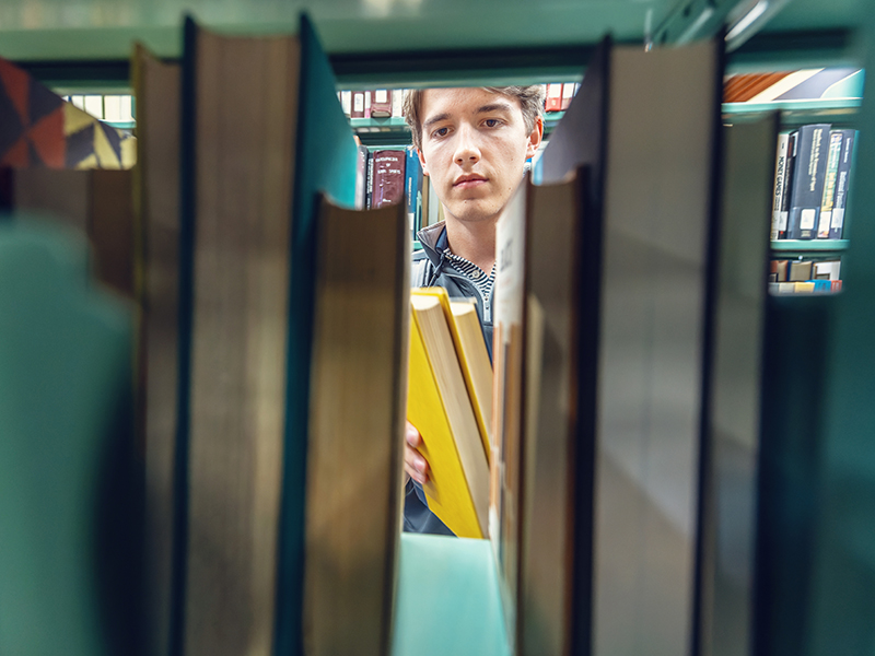 a student lkooking though a stack of books