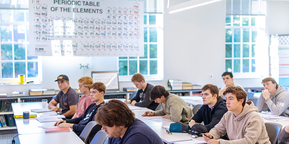 a chamistry classroom full of students with a periodic chart in the background