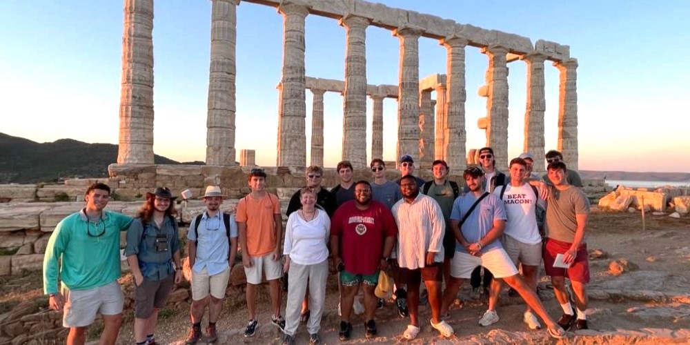 Students with their professor in front of ancient columns in Greece