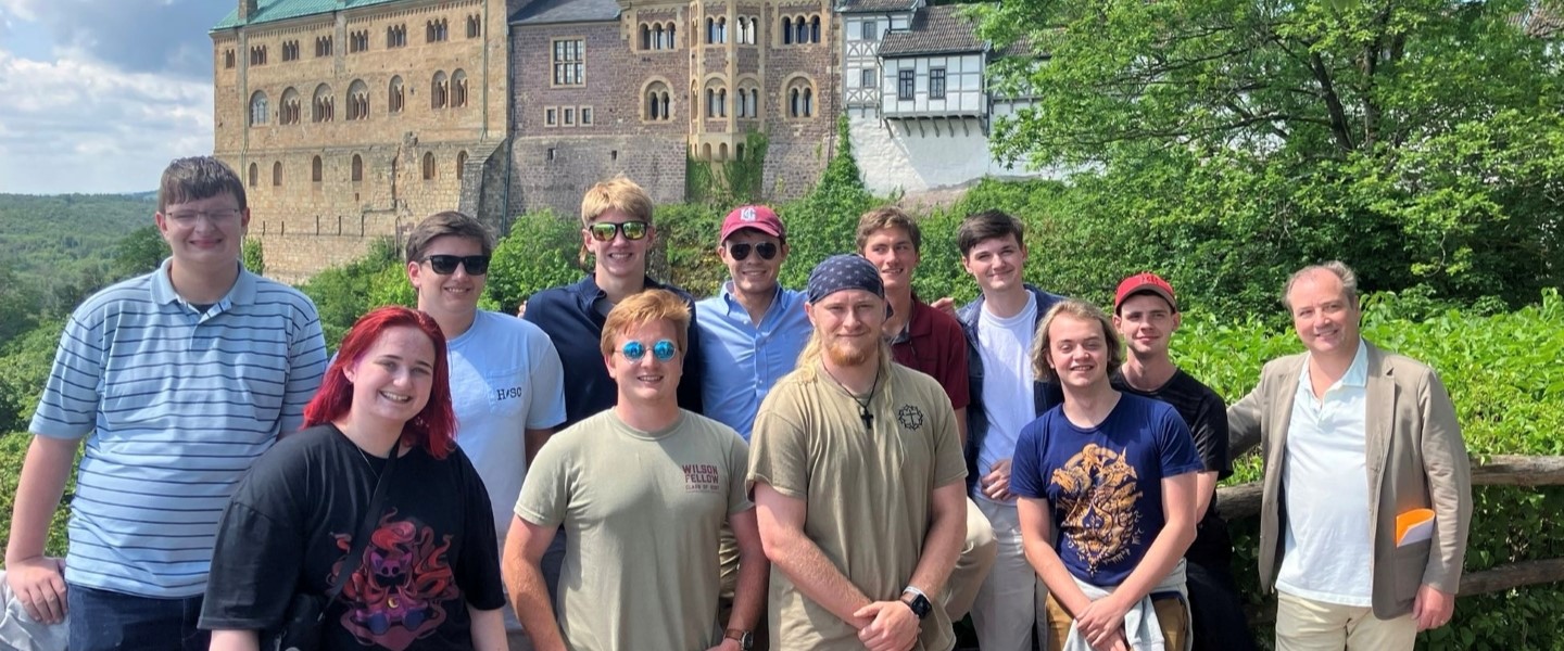 Students and professor posing in front of a countryside castle in Muenster, Germany