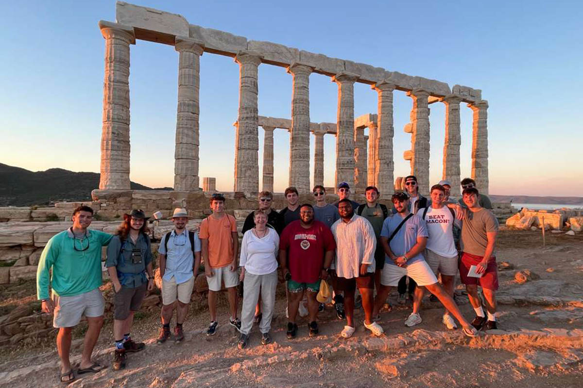 Students and professor posing at sunset in front of ancient ruins in Greece