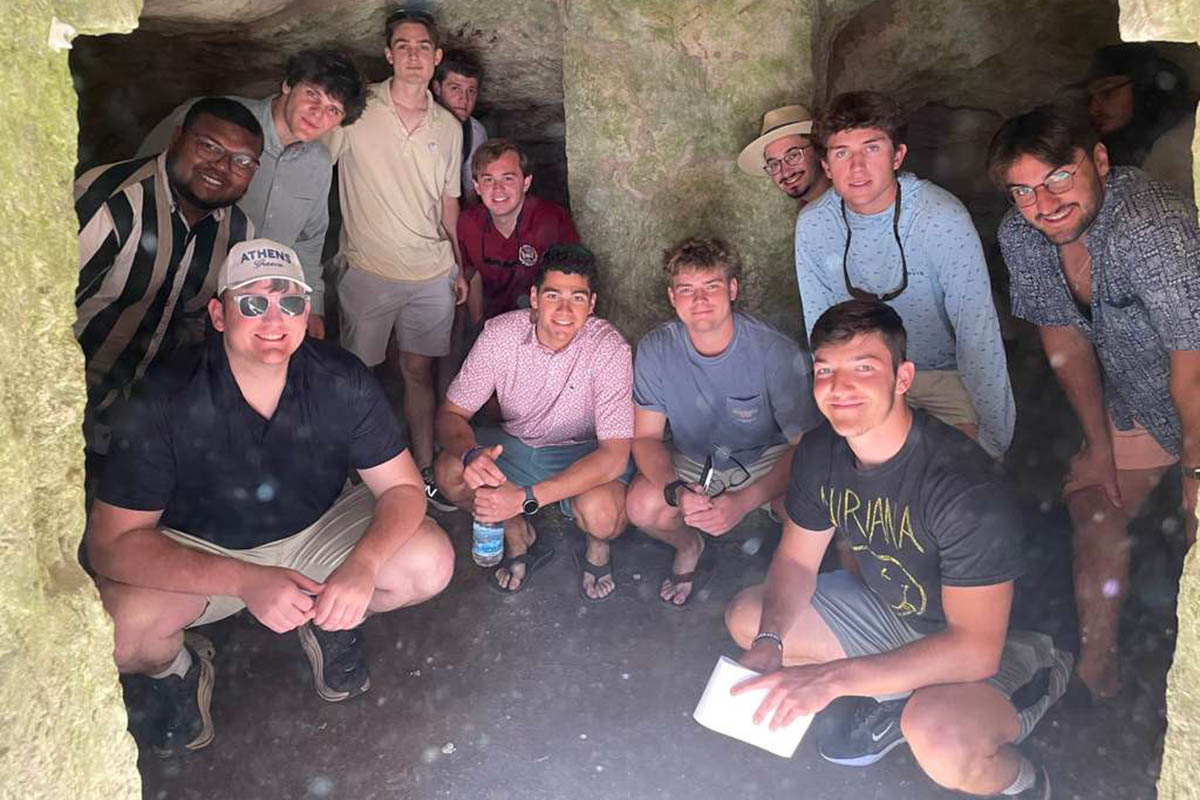 students crouching beneath Roman aqueducts