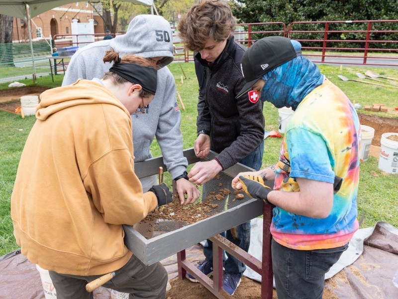 students sifting through archaeological finds on a dog site