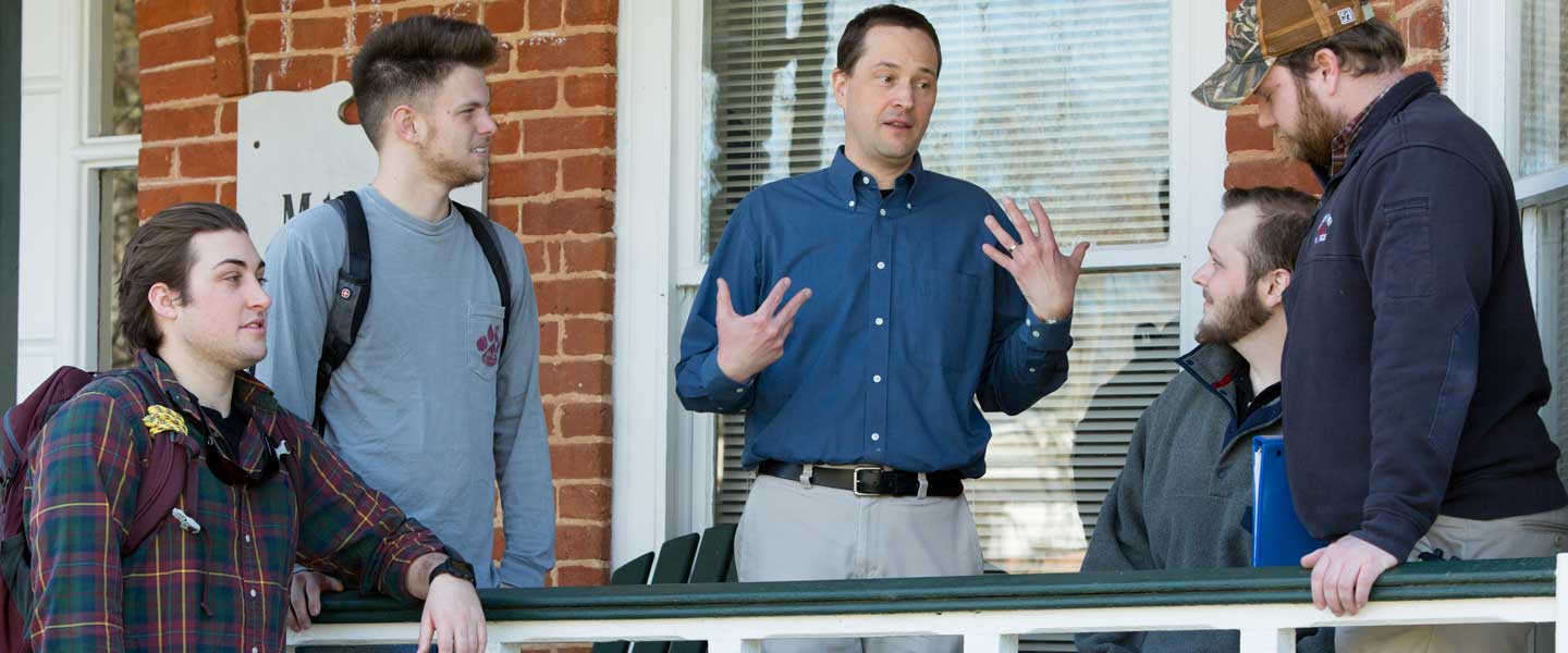 a professor talking to students on a porch