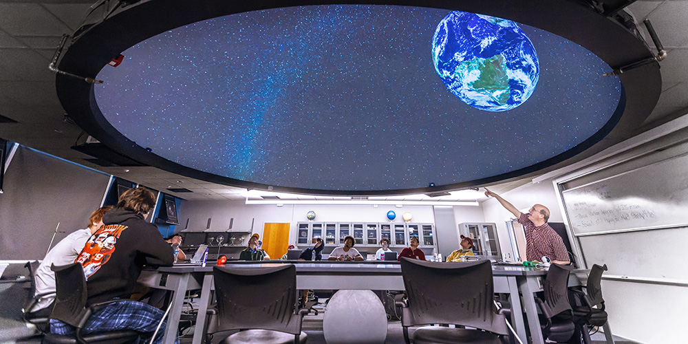 students and professor in a large classroom planetarium