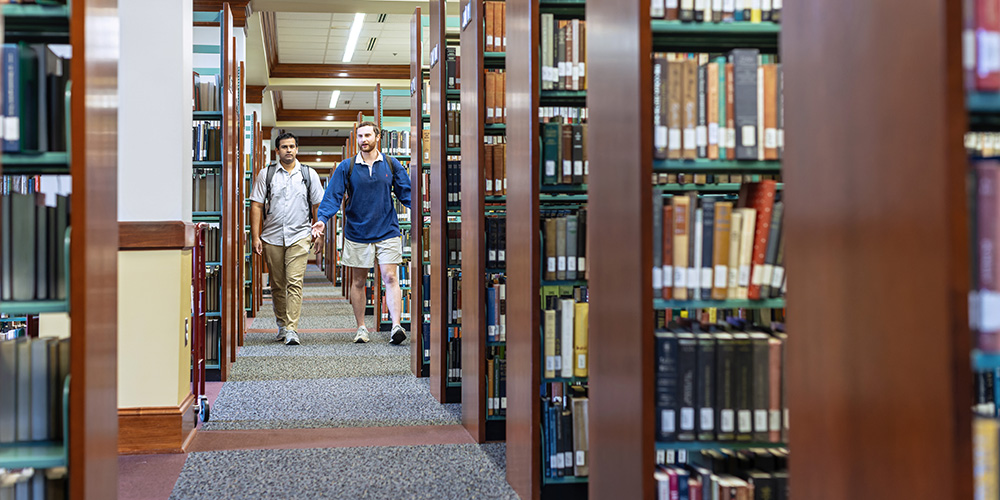 students walking through the library stacks