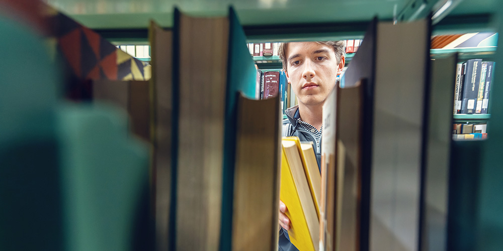 a student looking through a bookshelf in the library